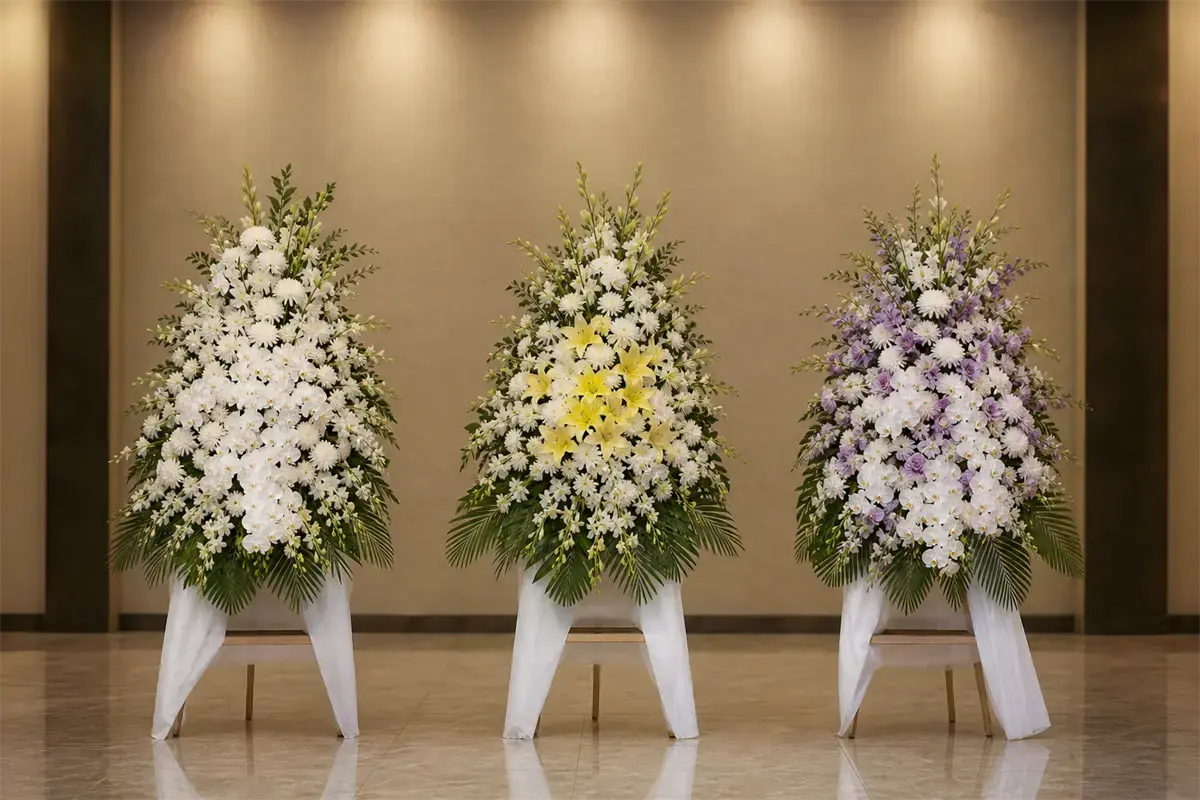Ba kệ hoa viếng cùng dáng đặt cạnh nhau: một kệ tông trắng thuần, một kệ trắng phối vàng, một kệ trắng phối tím nhạt